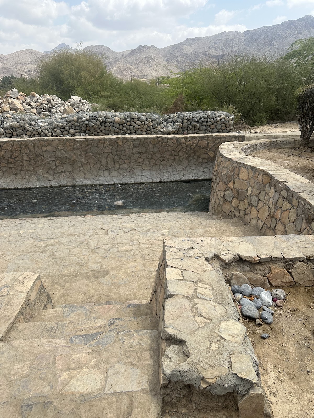 Falaj Daris Park walkway shaded by trees in Nizwa