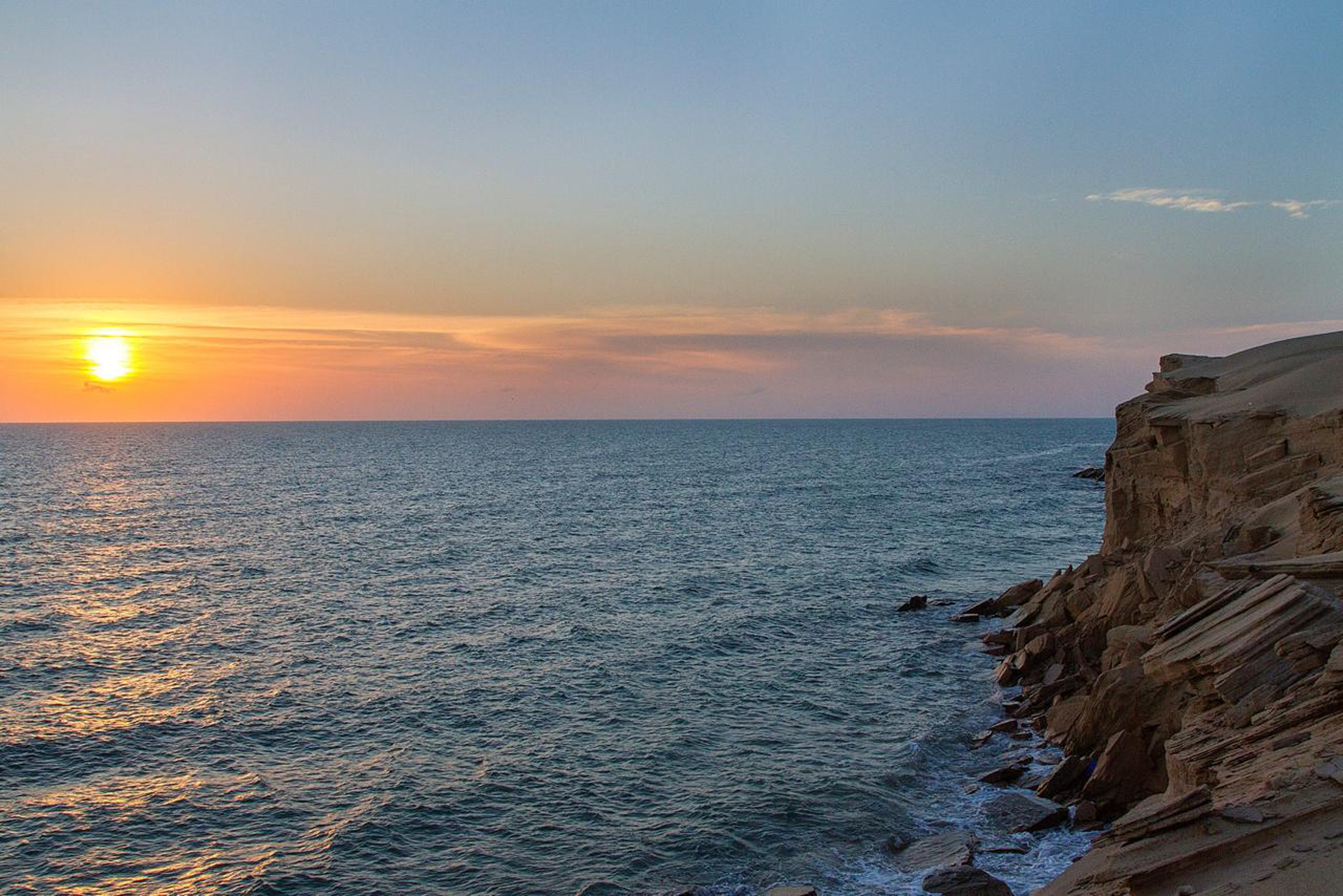 Sunset over the sea cliffs at the southern end of Fins Beach on the Quriyat-Sur coast road