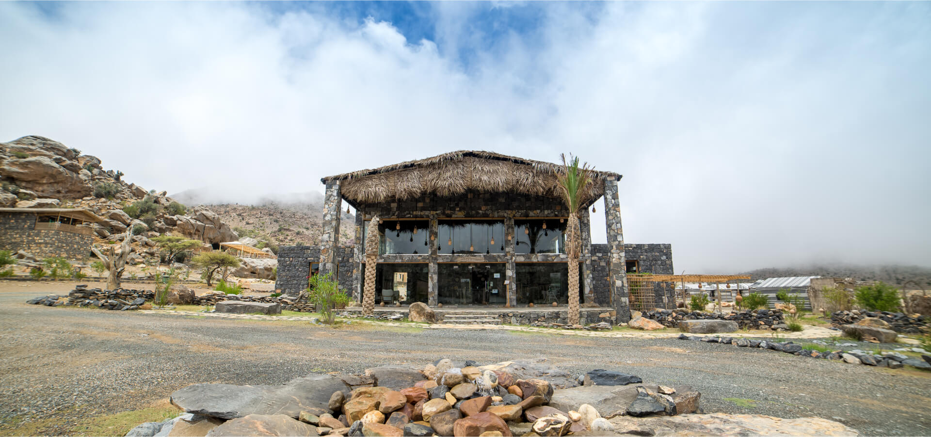 Stone-and-barasti reception lodge of Sama Heights Resort in the Jebel Shams mist