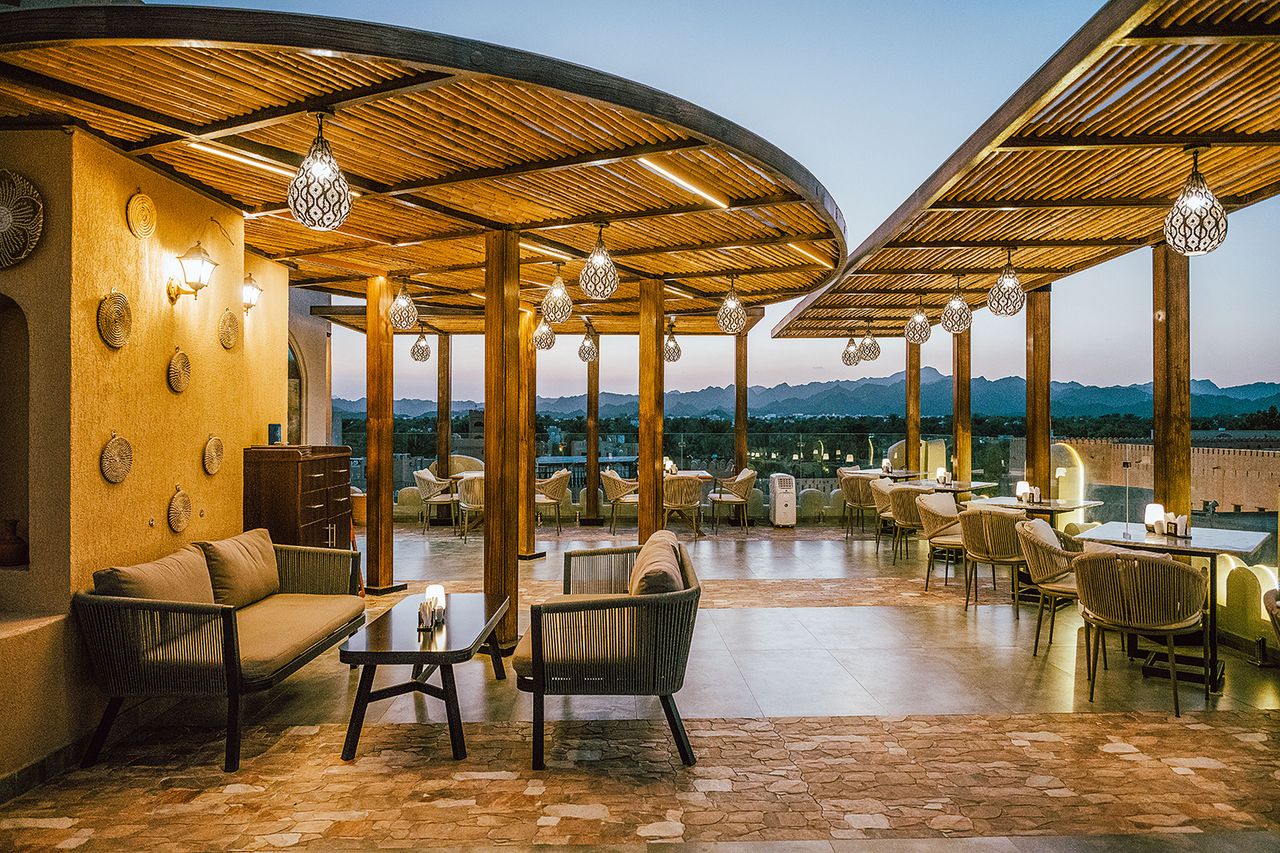 Rooftop seating at Tamrah Restaurant & Cafe in Nizwa with mountain views at dusk